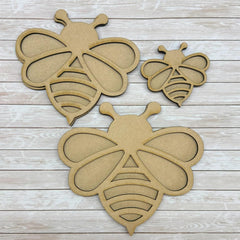Three cardboard bee shapes on a wooden surface