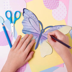 Children's hands working on a craft project with scissors, markers, and a butterfly template on a colorful background.