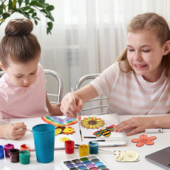 Two young girls painting with watercolors at a table.