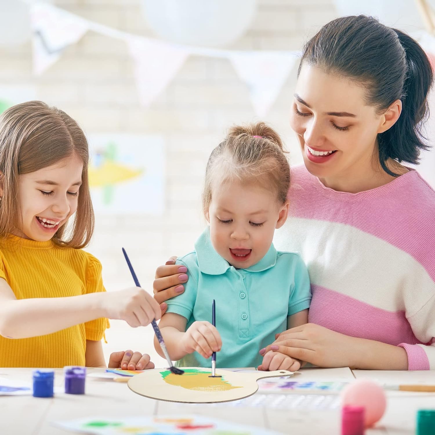 Woman and two children painting together at a table