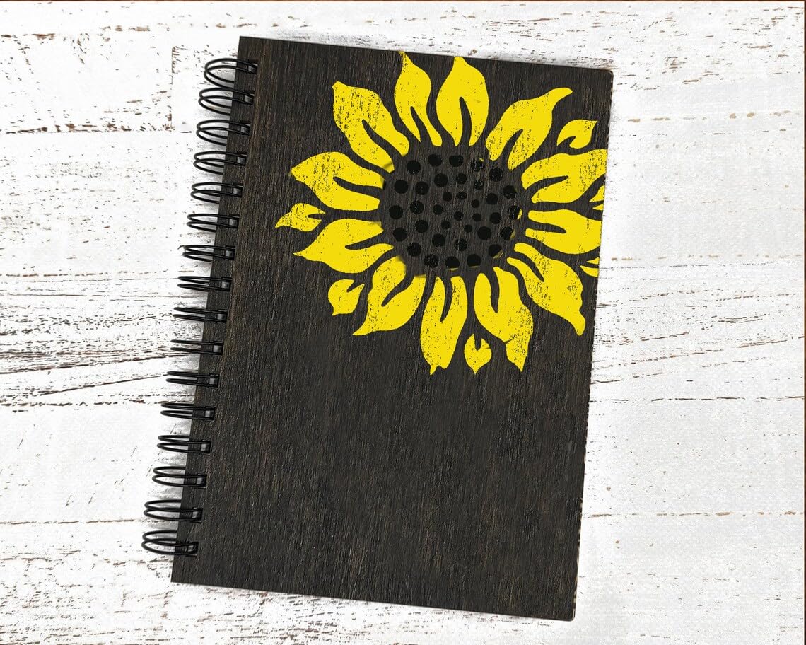 Black notebook with a yellow sunflower design on a white wooden surface