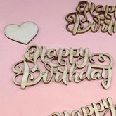 Wooden 'Happy Birthday' and heart decorations on a pink background