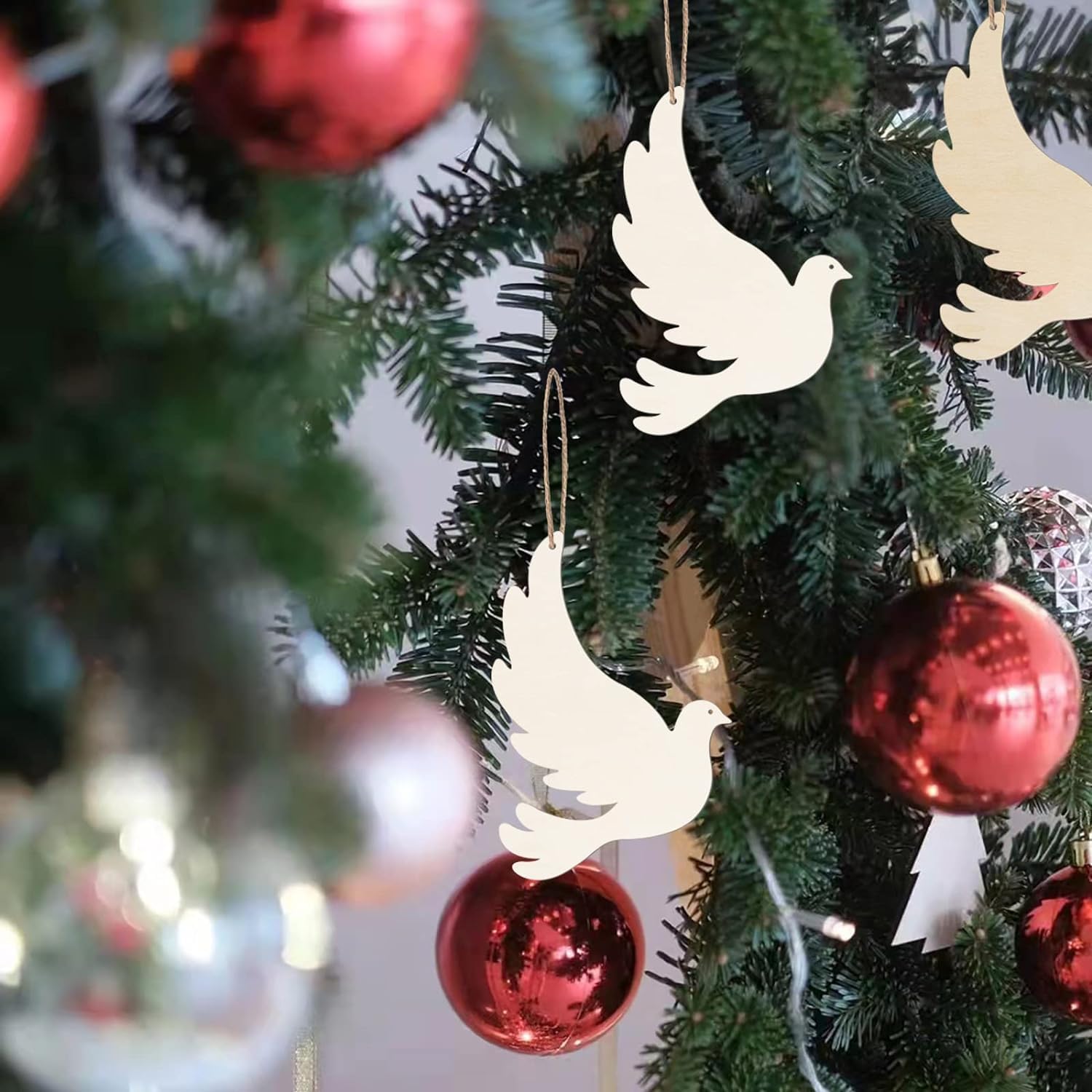 White dove ornaments on a Christmas tree with red and gold decorations.