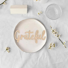 Round ceramic plate with 'Grateful' text on a light background with flowers