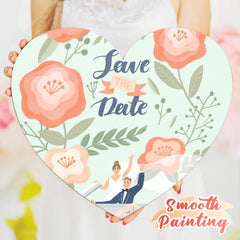 Heart-shaped card with floral design and 'Save the Date' text, held by a person.