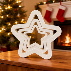 Stack of white star-shaped objects on a wooden surface with Christmas decorations in the background.