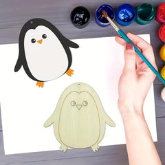 Hand painting a cartoon penguin with watercolors on a white sheet of paper.