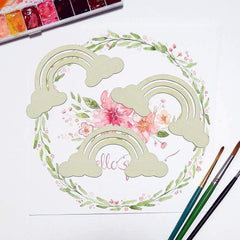 Artistic watercolor design of rainbows and flowers with paintbrushes and watercolor pan on a white background