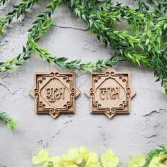Two wooden decorative items with engraved text on a light gray surface with green leaves and yellow flowers.