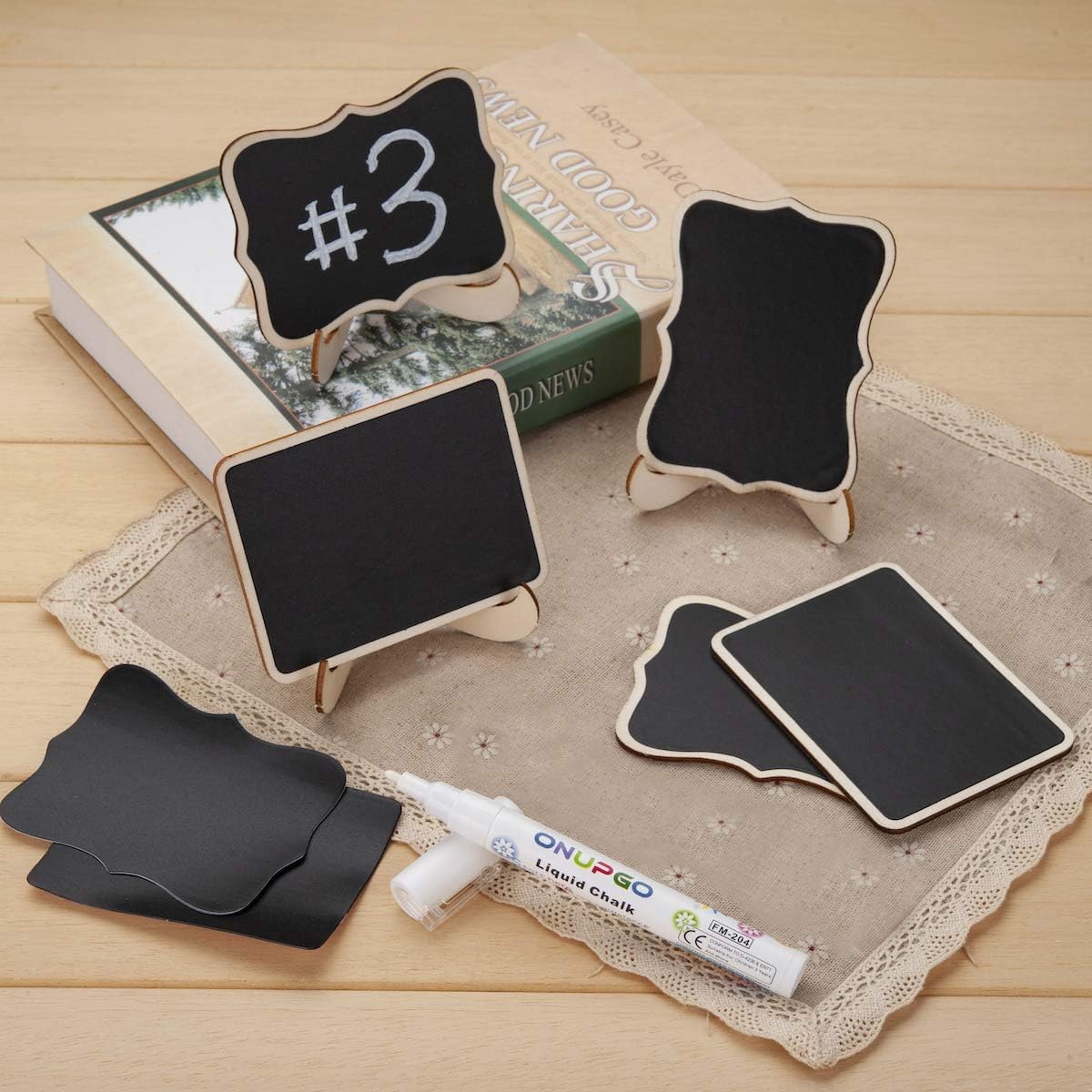 Small blackboards with stands, a marker, and a book on a wooden surface