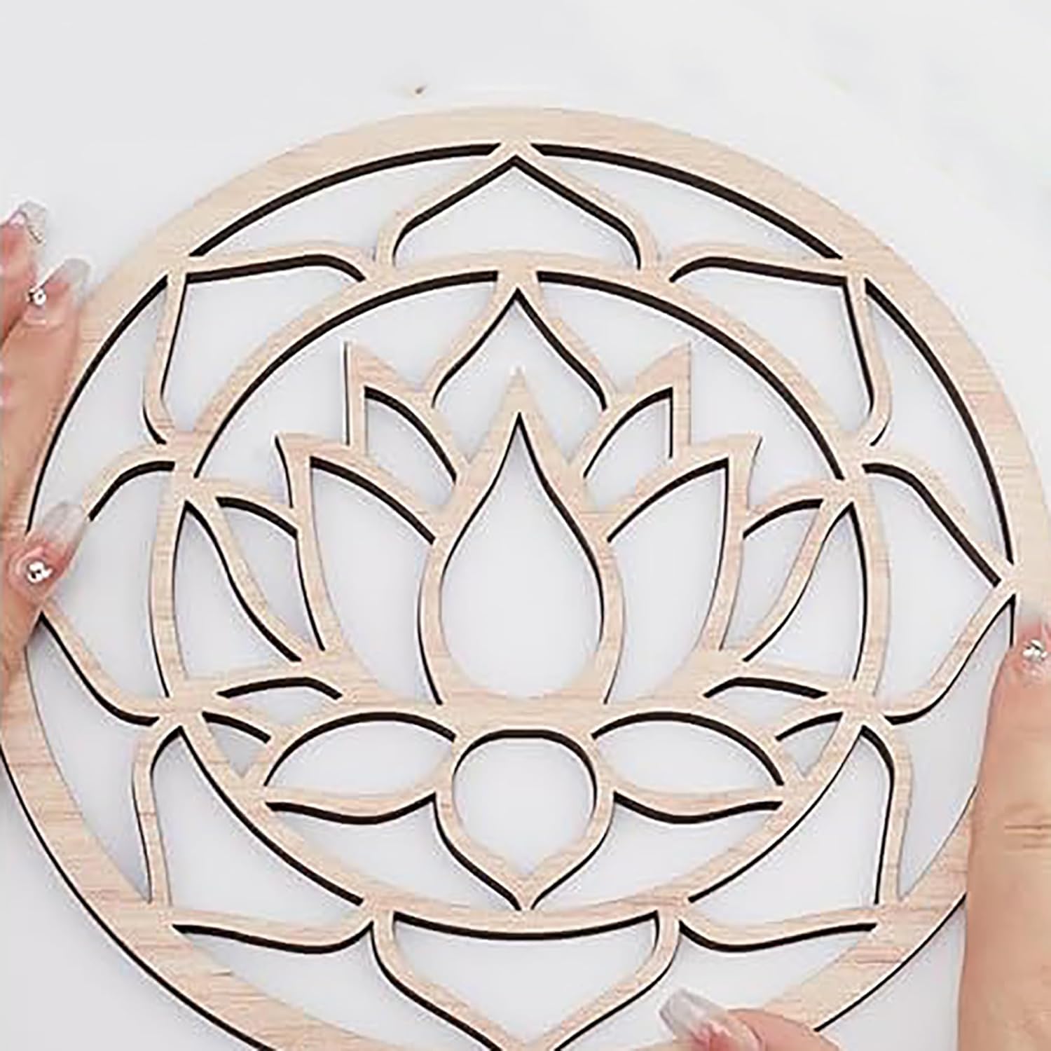 Wooden lotus flower wall art held by hands on a white background