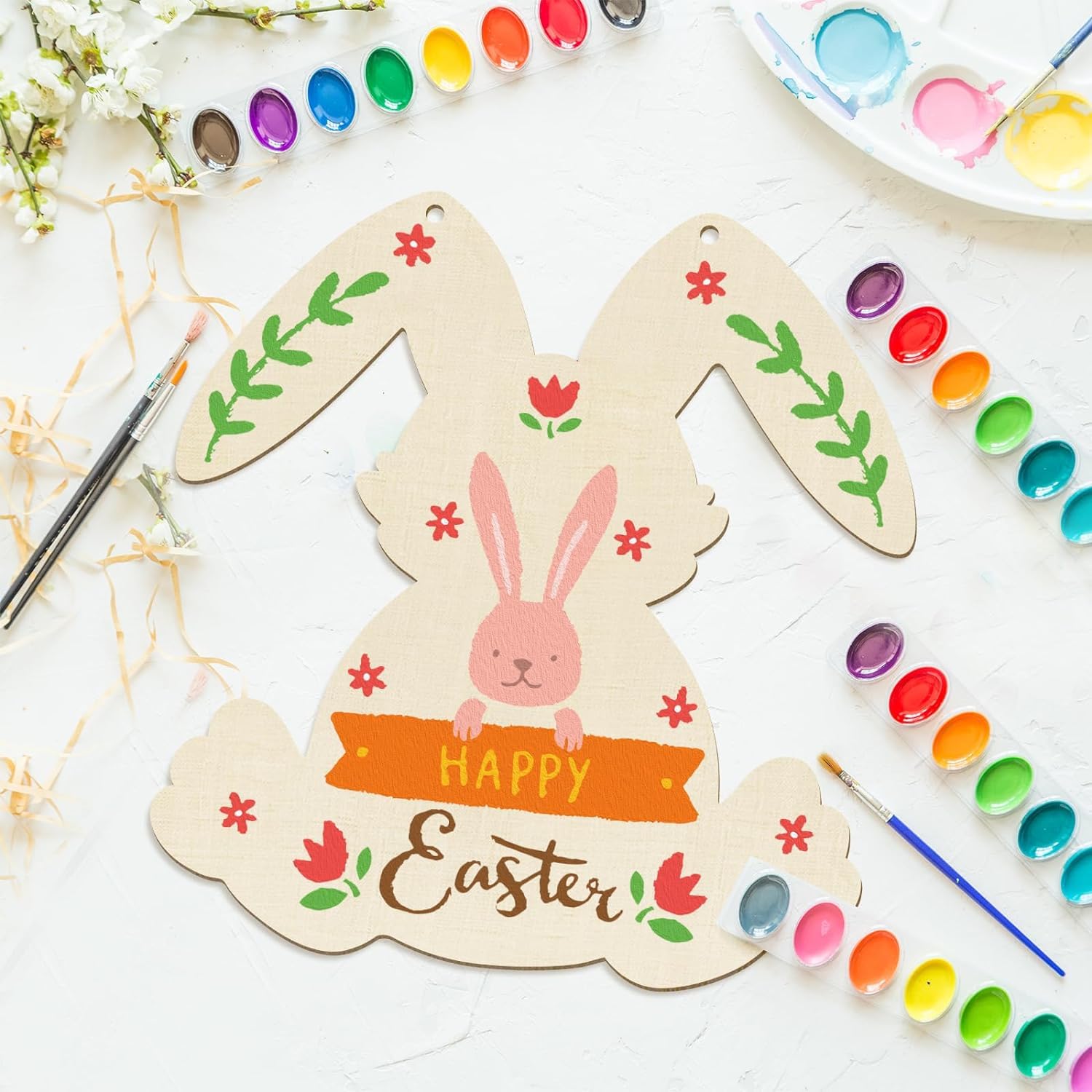 Decorative Easter bunny card with paint supplies on a white surface