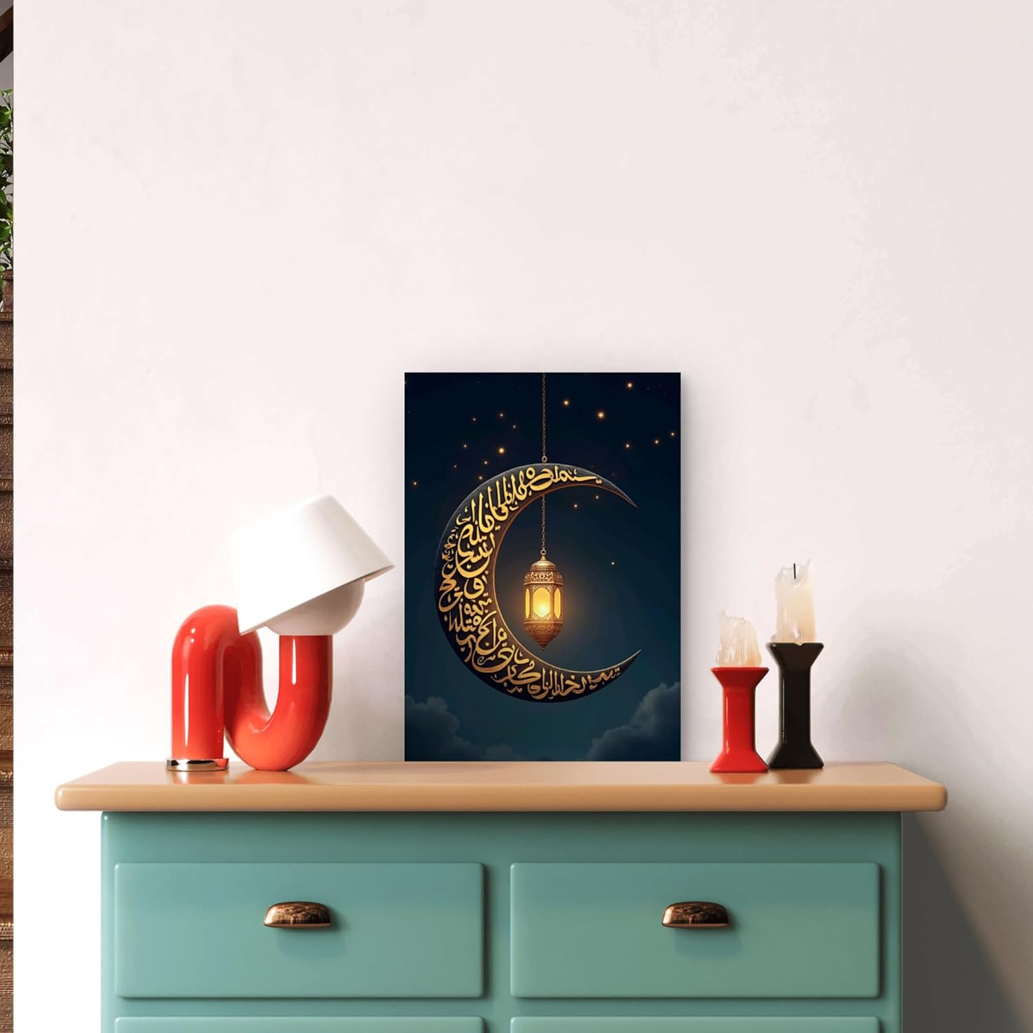 Decorative wall art with a crescent moon and lantern on a blue background, displayed above a teal cabinet.