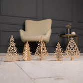 Set of decorative wooden Christmas trees on a marble surface with a chair and table in the background.