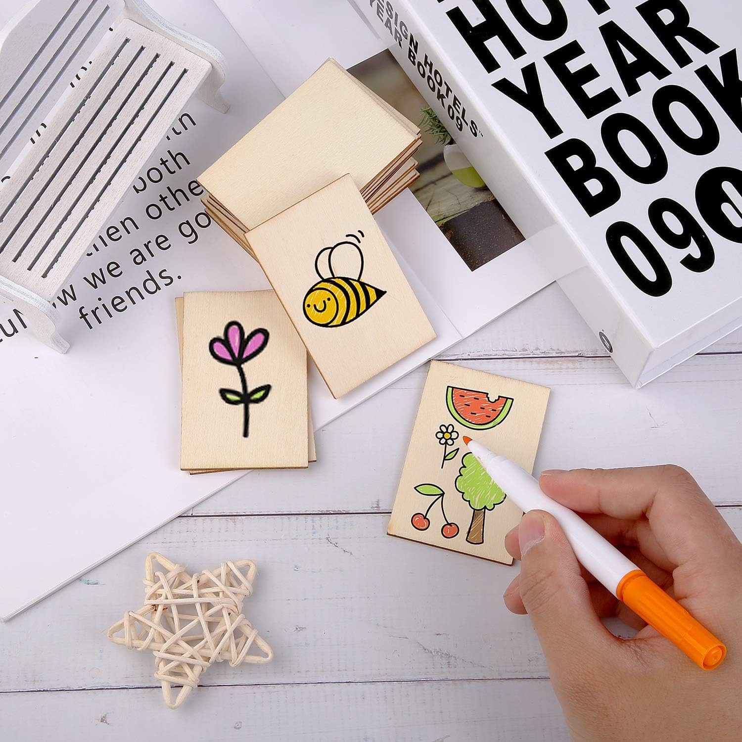 Set of small wooden stamps with illustrations on a white surface, with a hand holding a marker.
