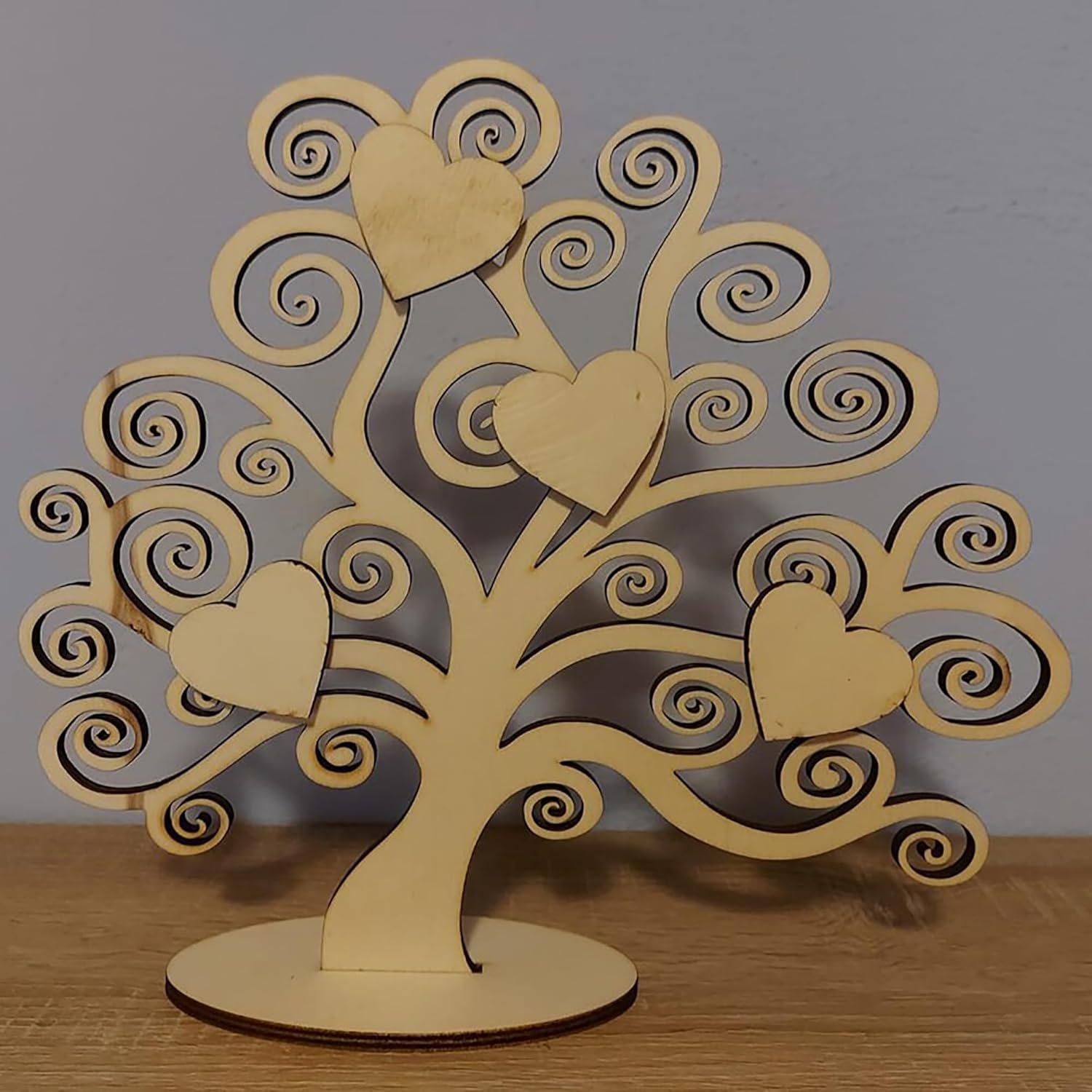 Wooden tree-shaped decorative item with heart designs on a wooden surface.