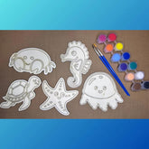 White outlines of sea creatures on brown paper with paint and brush