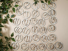 Wooden numbers on a beige background with green leaves