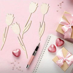 Pink tulips, heart-shaped candies, a pen, and small gift boxes on a pink background