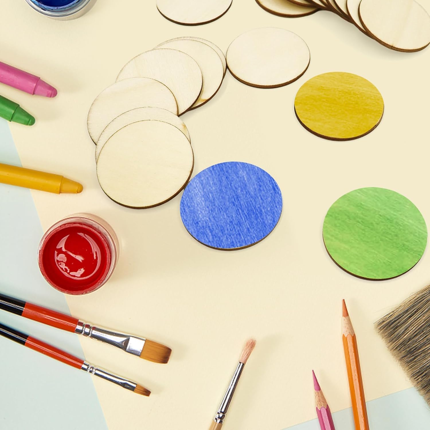 Colorful wooden circles, paintbrushes, and crayons on a light surface