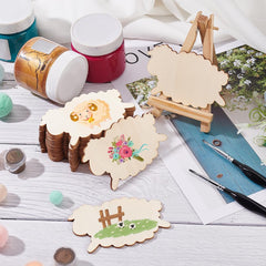 Decorative sheep-shaped wooden boards with paint cans and brushes on a table