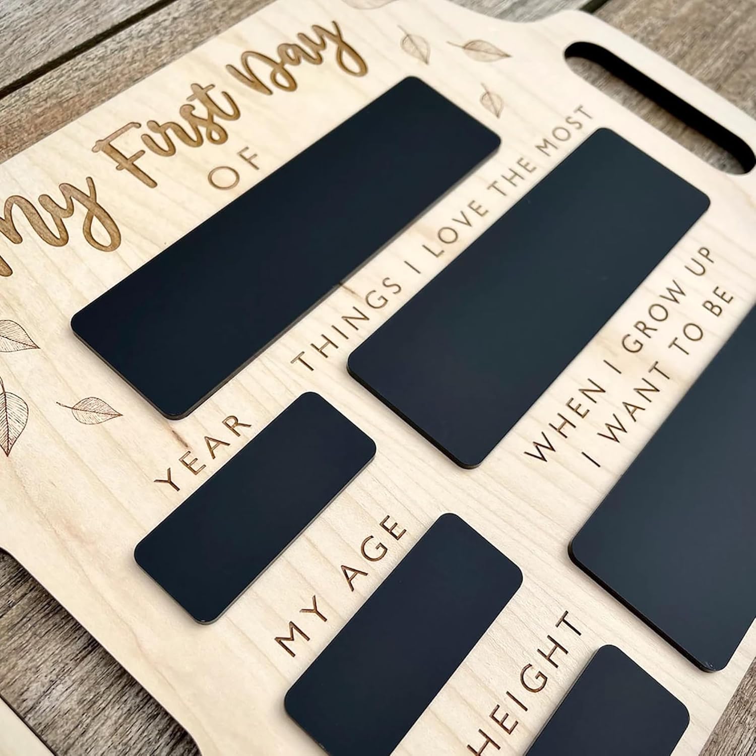 Wooden board with engraved text for a child's first day of school, featuring blank black panels.