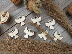 Wooden angel ornaments on a rustic wooden surface with acorns and straw.