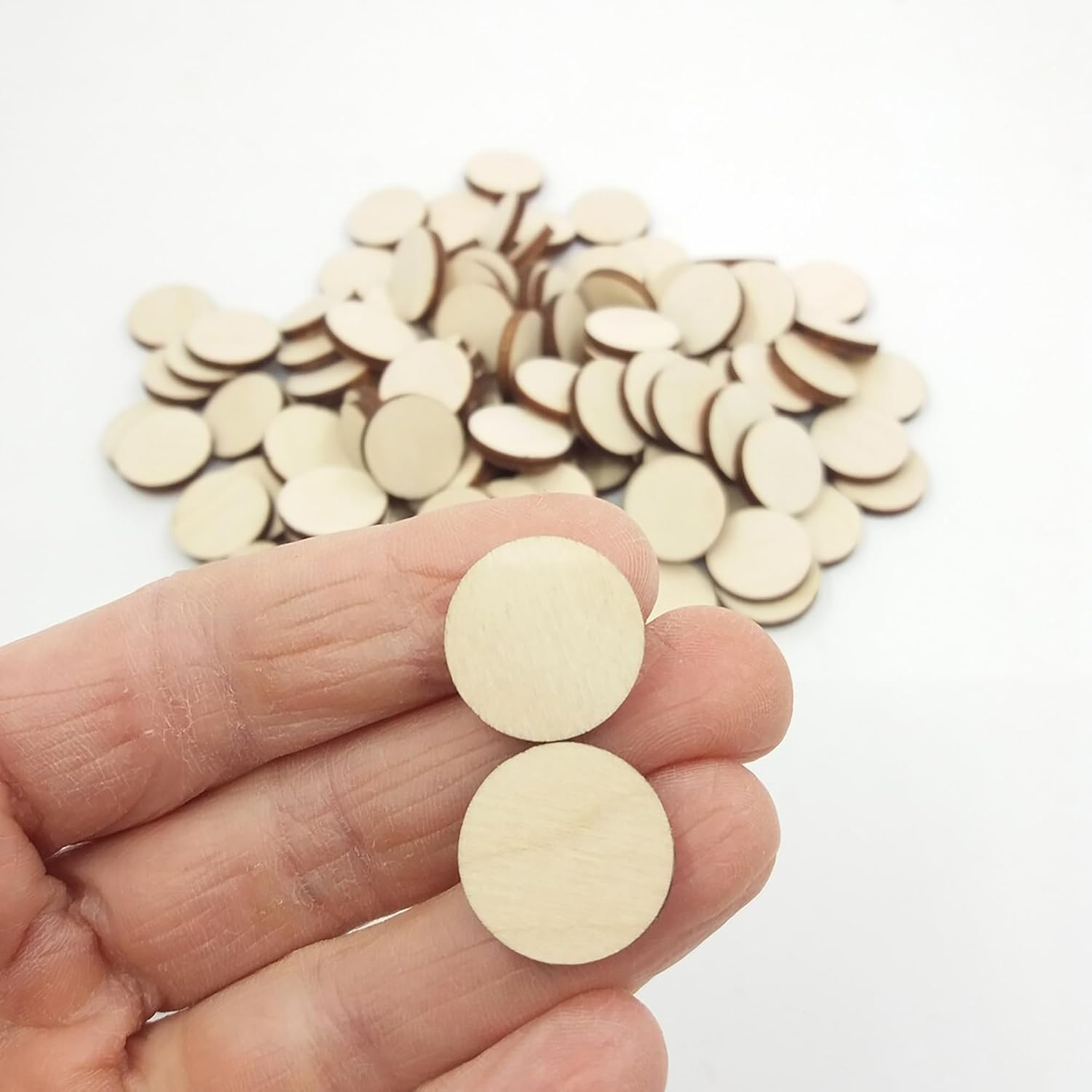 Wooden discs held in a hand with more discs on a white background