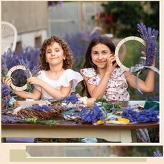 Two young girls making wreaths with lavender and other materials outdoors.
