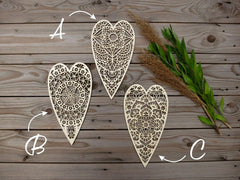 Three ornate heart-shaped cutouts on a wooden surface with decorative elements.