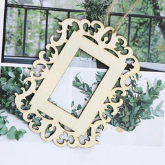 Decorative wooden frame with intricate cut-out patterns hanging on a wall with greenery.