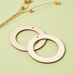 Two wooden rings on a light green background with dried flowers.