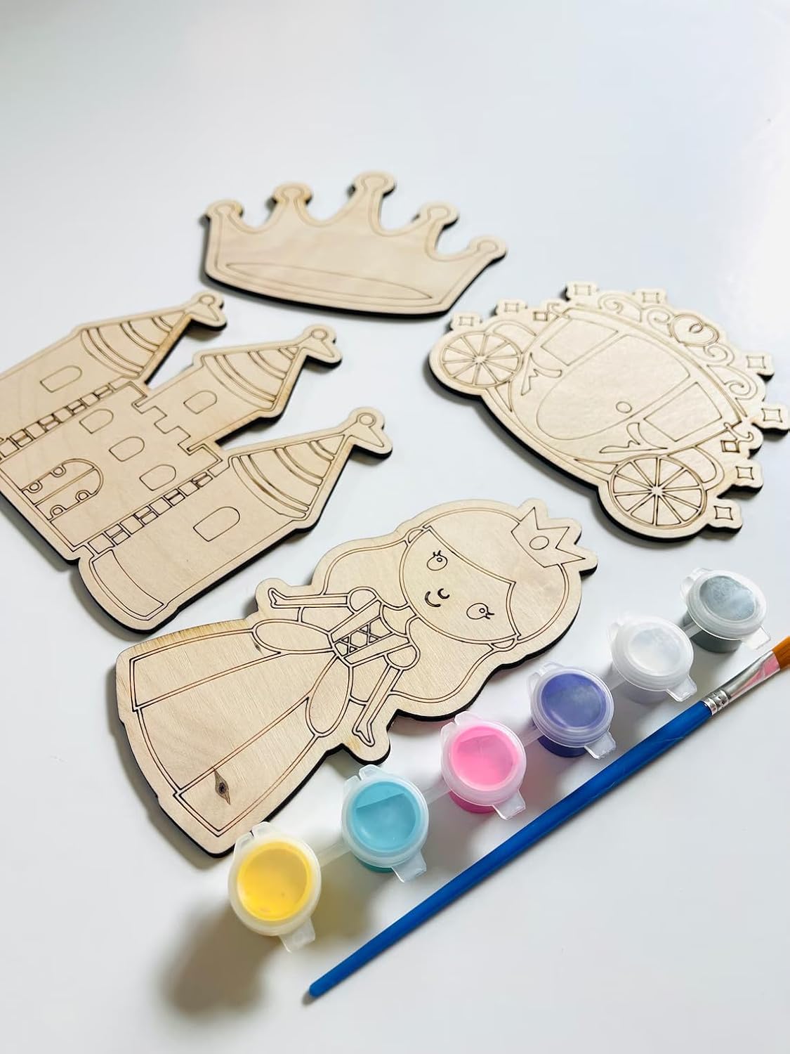 Wooden princess and castle cutouts with paint supplies on a white background