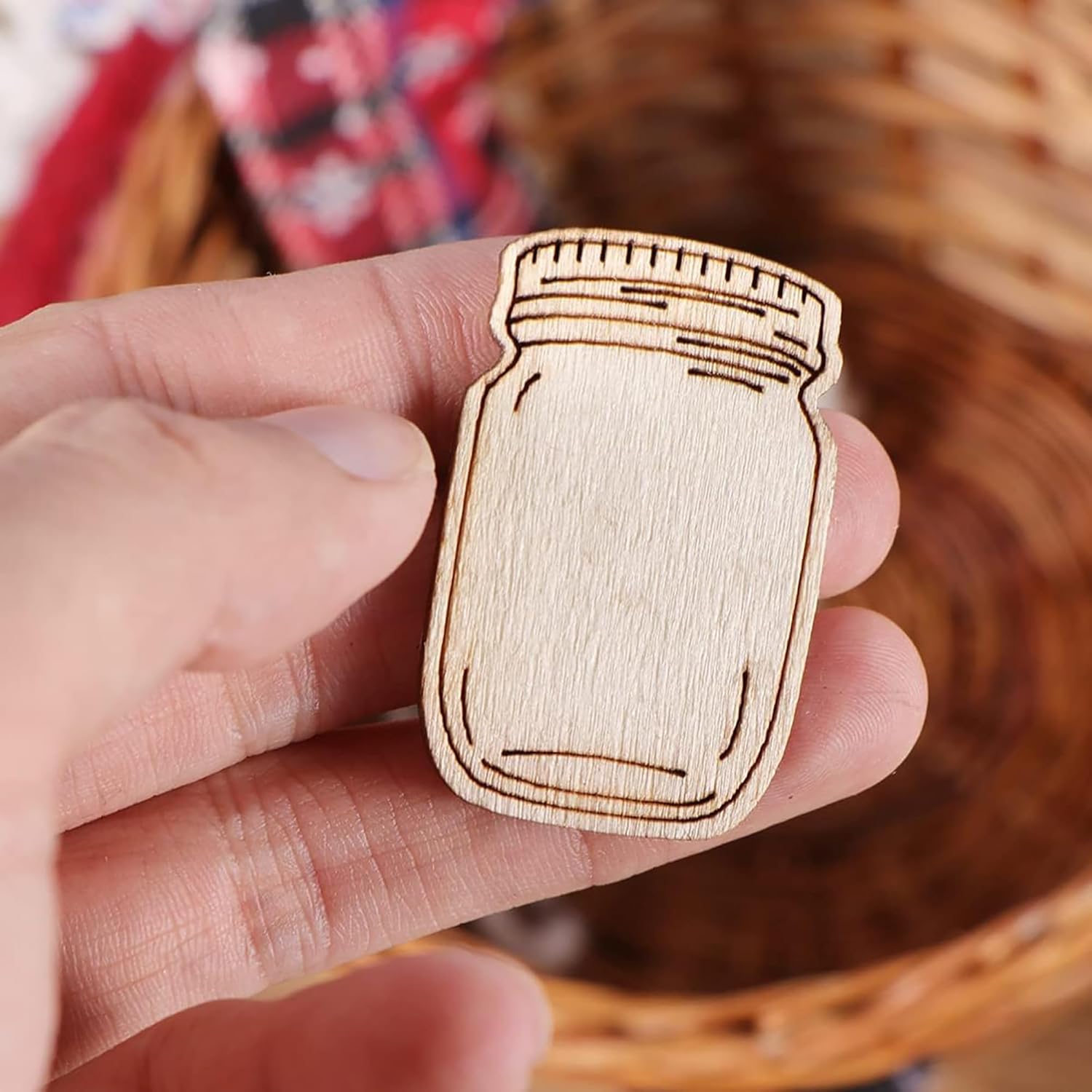 Wooden mason jar ornament held in a hand with a wicker basket in the background