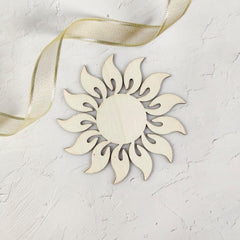 Decorative sun-shaped ornament with a gold ribbon on a light gray background