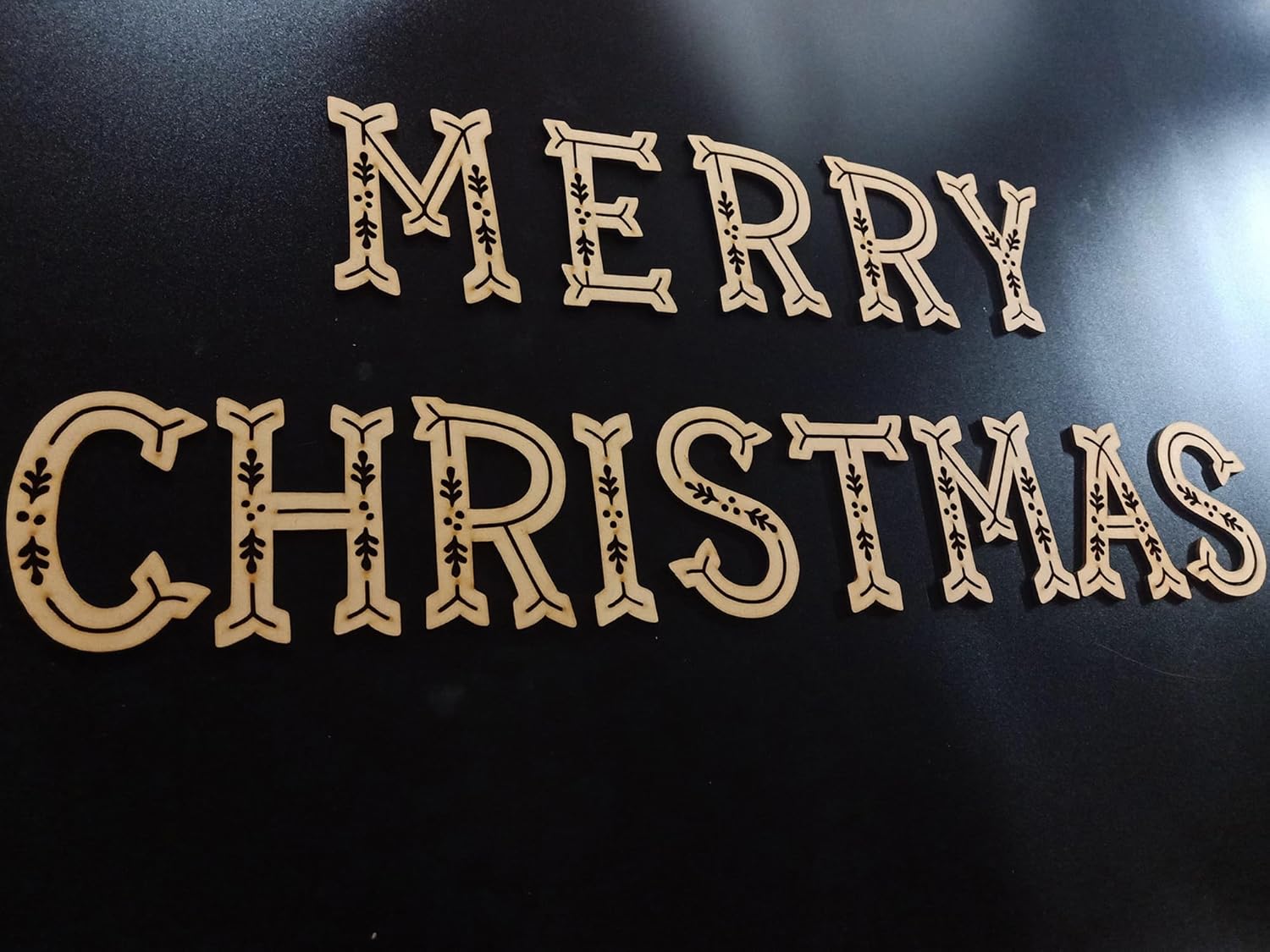 Decorative wooden letters spelling 'Merry Christmas' on a black background
