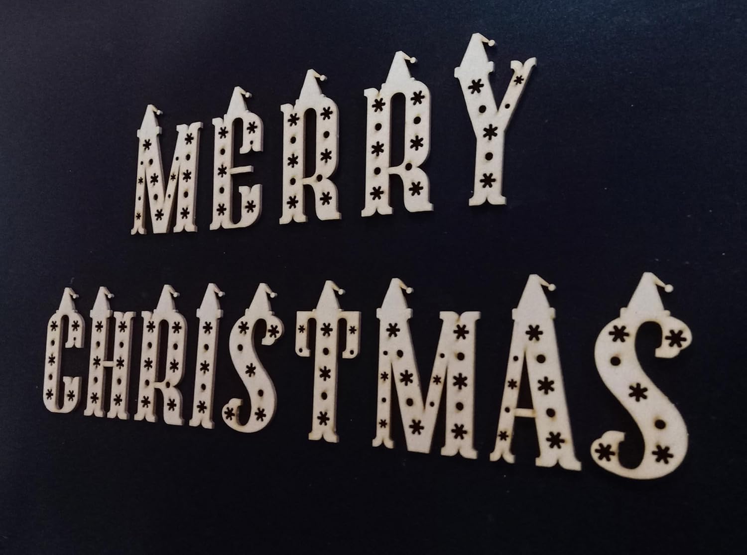 Wooden Christmas decoration with 'Merry Christmas' text on a black background