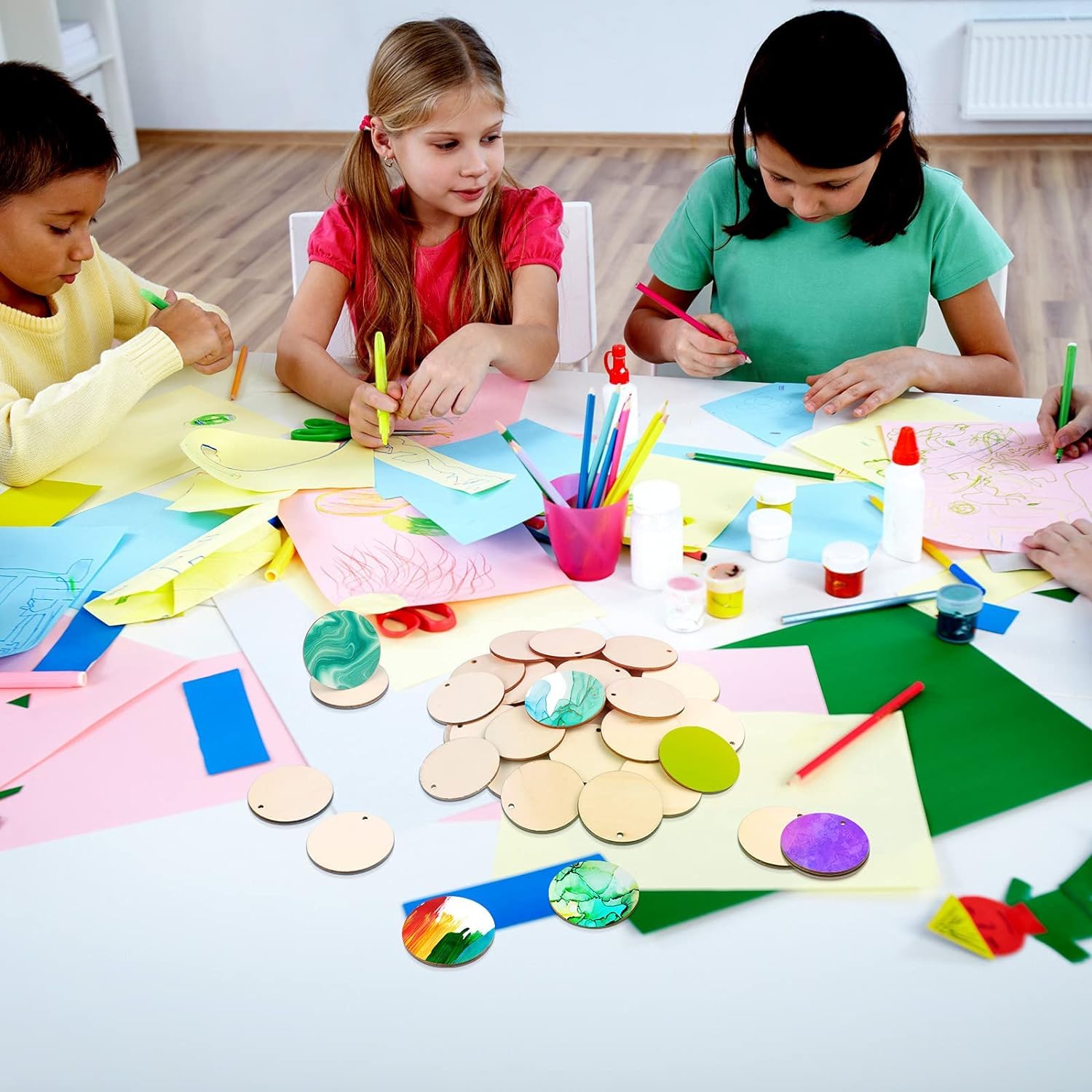 Children engaged in art activities with various materials on a table.