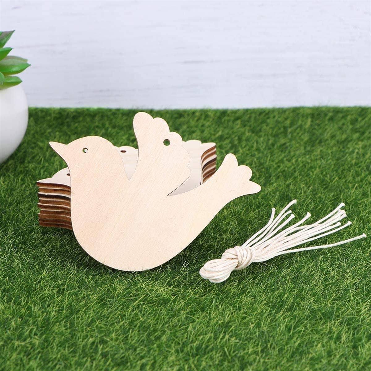Wooden bird-shaped decoration with a tassel on grass
