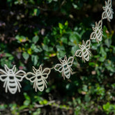 String of bee-shaped decorations against a green leafy background
