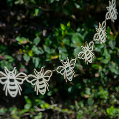 String of bee-shaped decorations against a green leafy background