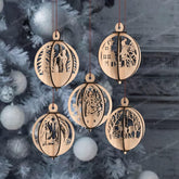 Wooden Christmas ornaments with intricate cut-out designs on a blurred Christmas tree background.