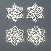 Four white snowflake-shaped cutouts on a dark background
