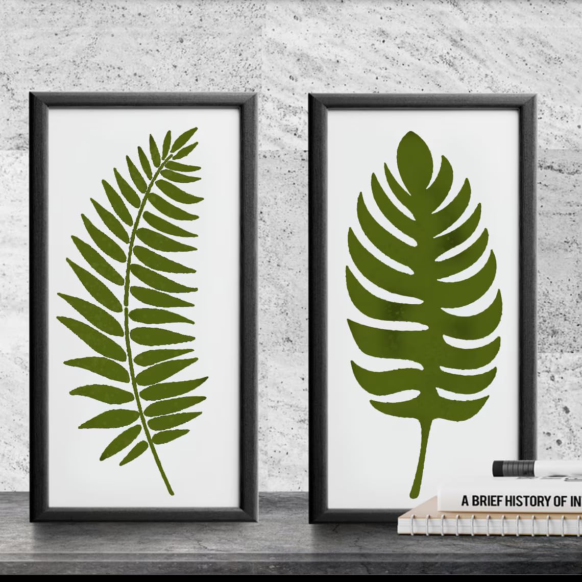 Two framed prints of green leaf designs on a concrete wall.