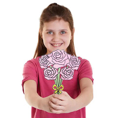 Girl wearing a pink shirt with a floral design, holding the shirt against a white background