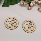 Two wooden OM symbol coasters on a light surface with flowers in the background