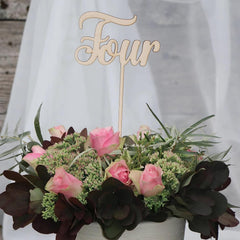 Floral arrangement with a 'Four' wooden cake topper on a white background