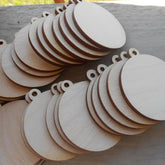 Stack of wooden round tags with holes on a gray surface
