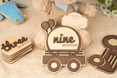 Wooden baby milestone cards with 'three months' and 'nine months' on a textured surface.
