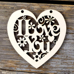Heart-shaped decorative cutout with floral and swirl designs on a wooden background